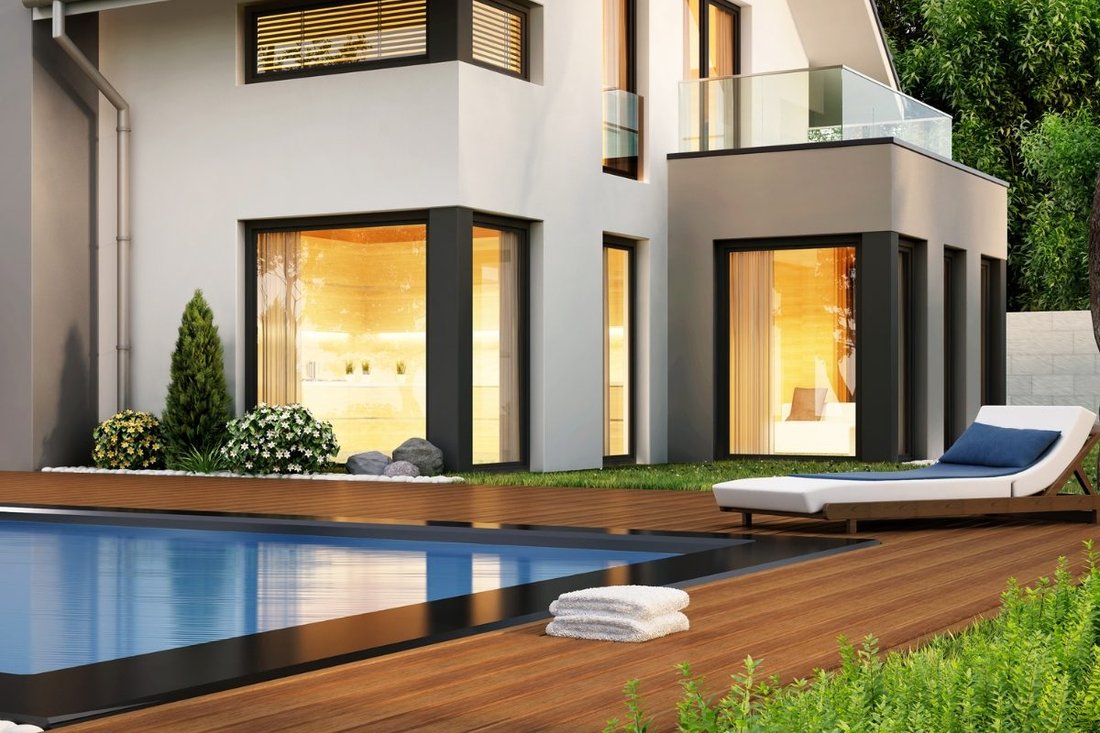 Wood pool deck with a lounge chair beside a backyard swimming pool
