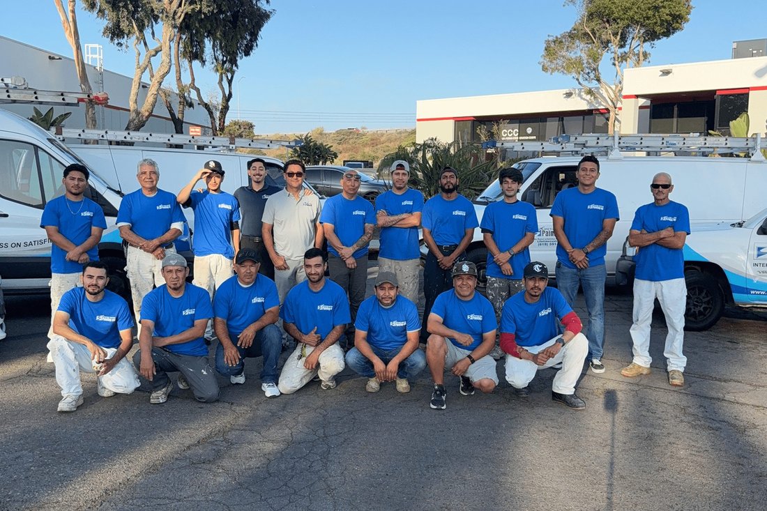 Lifetime Custom Painting crew in blue company shirts posing beside work vans