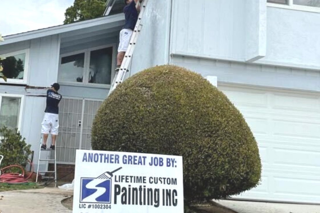 Lifetime Custom Painting yard sign showing the company license number outside a home being painted