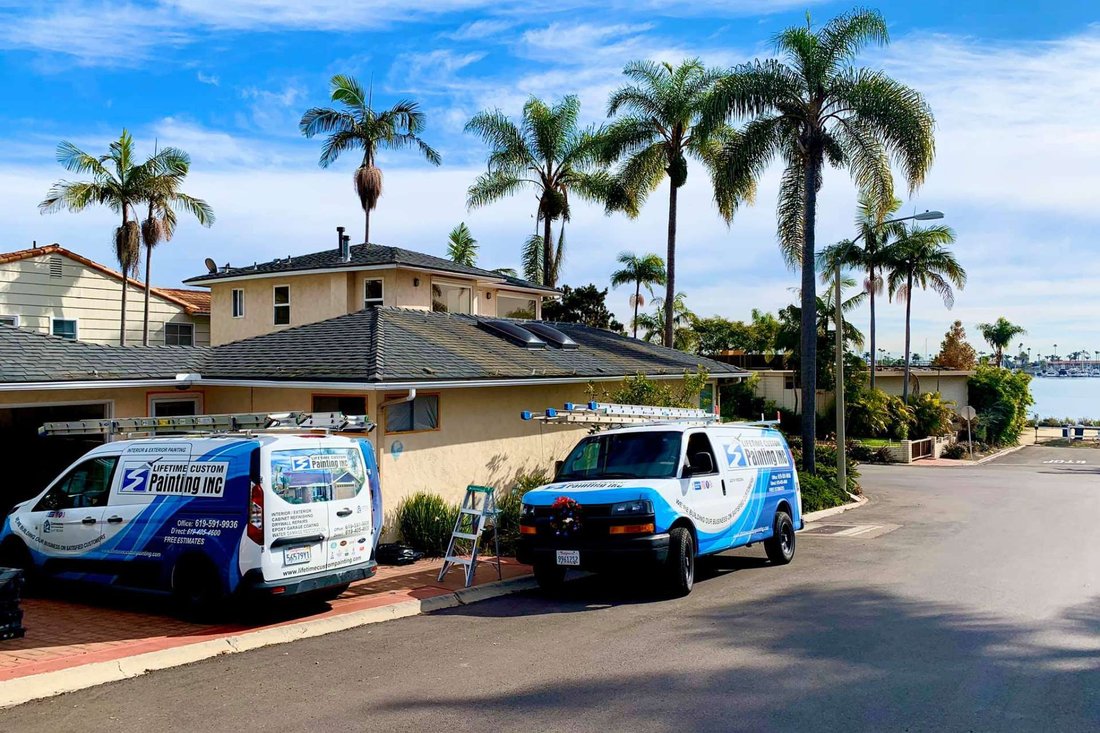 Lifetime Custom Painting work vans parked outside a palm-lined San Diego home