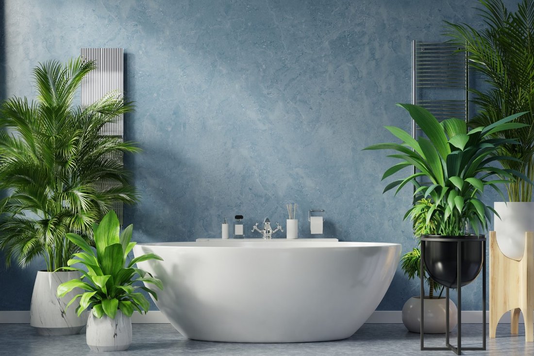 Bright bathroom with blue-gray painted wall, freestanding tub and potted plants
