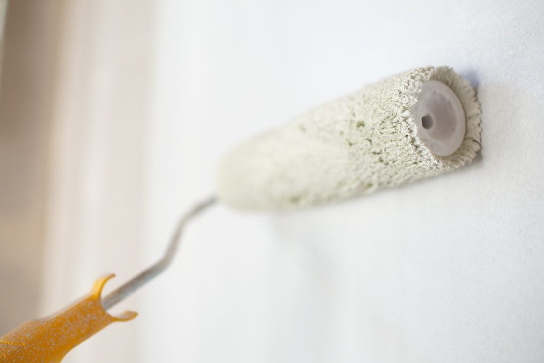 Paint roller applying a fresh white coat to a wall