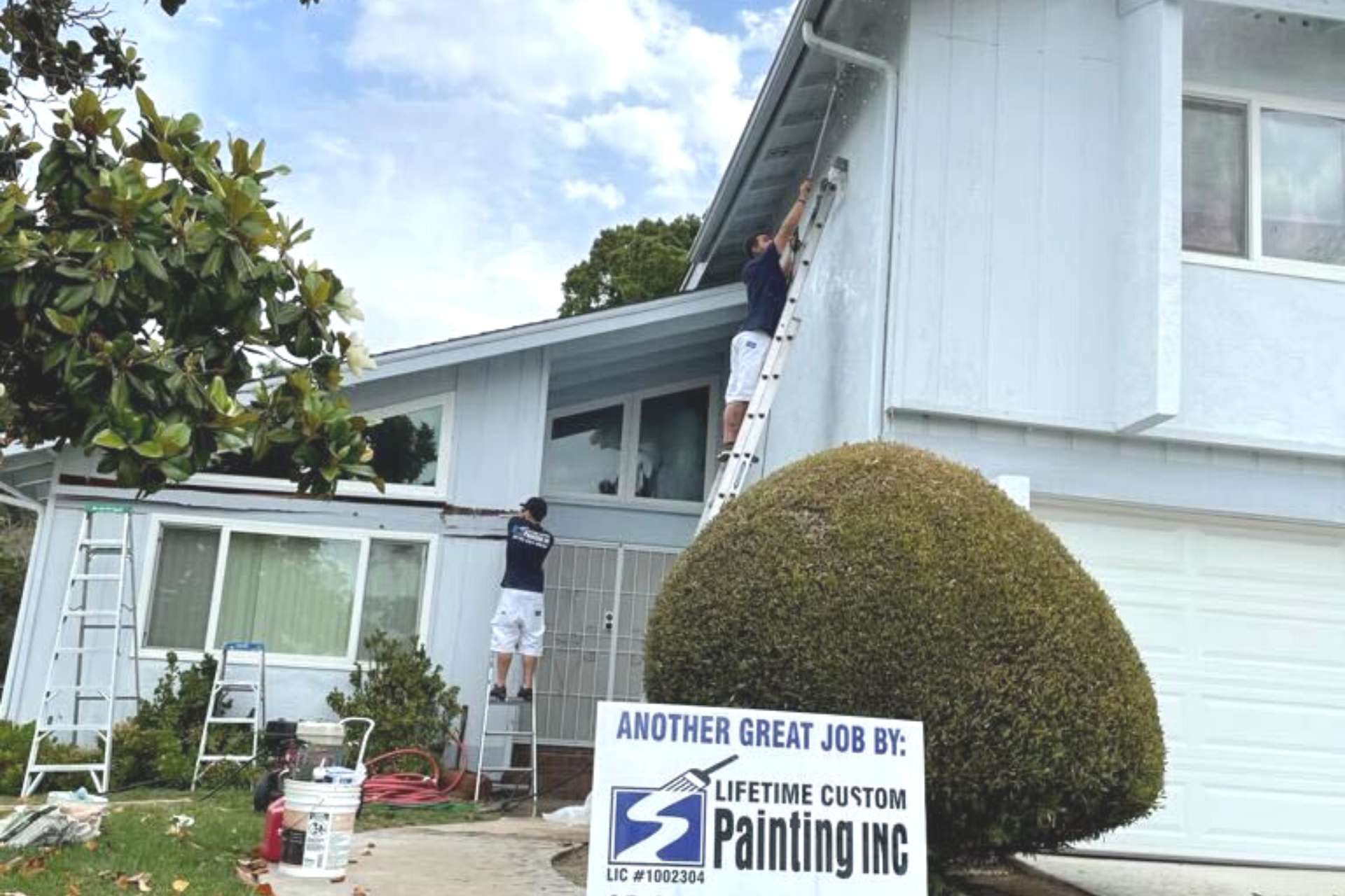 Two painters painting the exterior of a home.